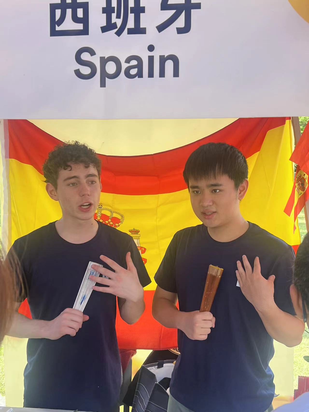 Spain's booth at the UNNC's Global Village: the country representative and a volunteer both teaching about Spanish fan language